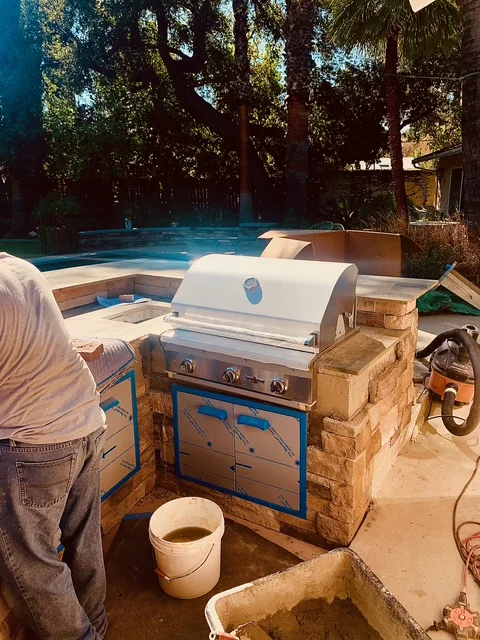 Stainless-steel grill installed in a curved outdoor BBQ island during construction.