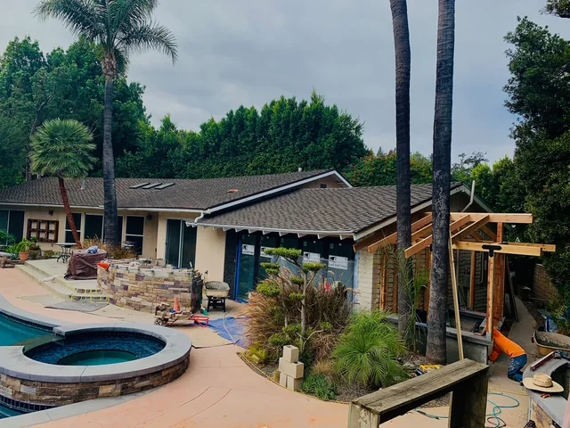 Outdoor BBQ island and poolside shower construction beside the residence.