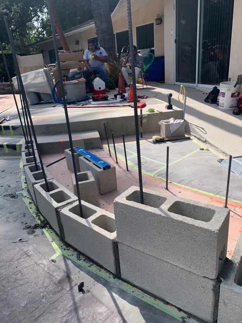 First course of masonry blocks laid out for a curved outdoor BBQ island.