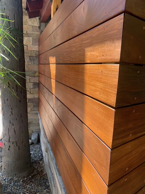 Close view of warm hardwood boards and stacked-stone masonry at the outdoor BBQ island.