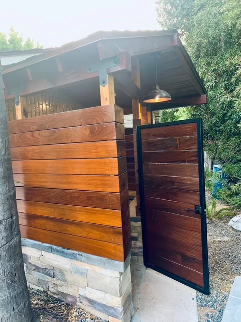 Timber poolside gate with dark metal hinges beside the outdoor shower.
