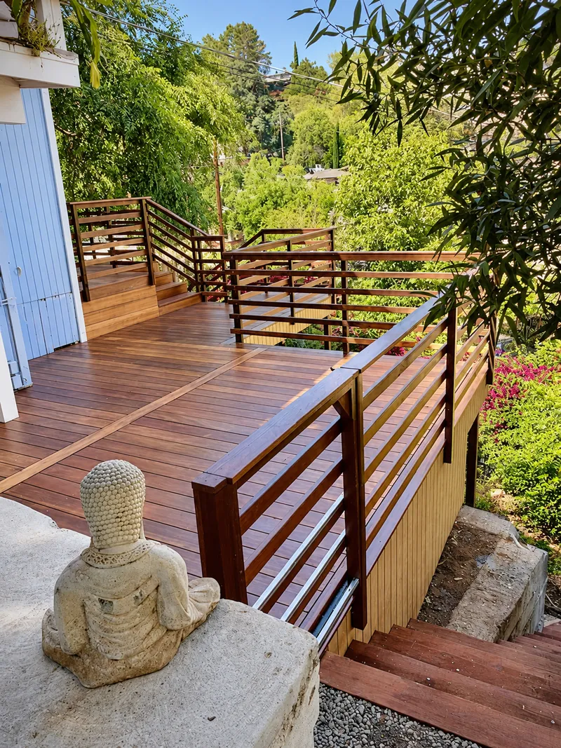 Stone Buddha statue beside timber deck railings, steps, and surrounding trees.