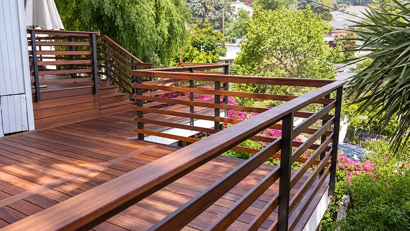 Timber deck and stairs with horizontal railings overlooking trees and garden planting.