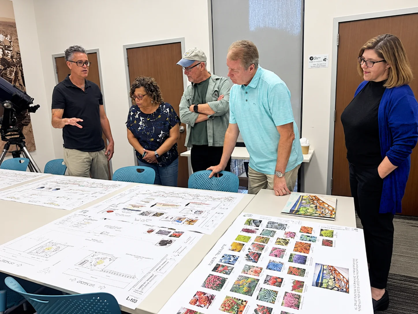 A group gathered around landscape drawings and planting presentation boards.